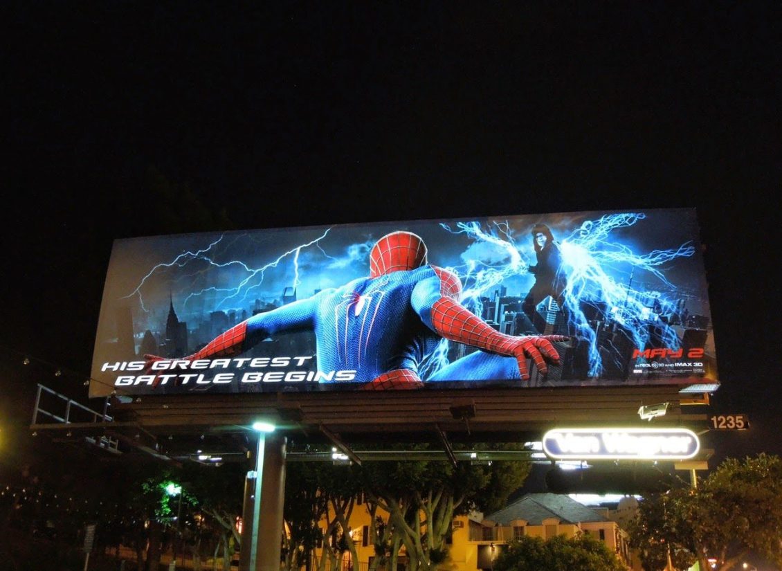 Lighted billboard with white lighted text advertising Spiderman at night